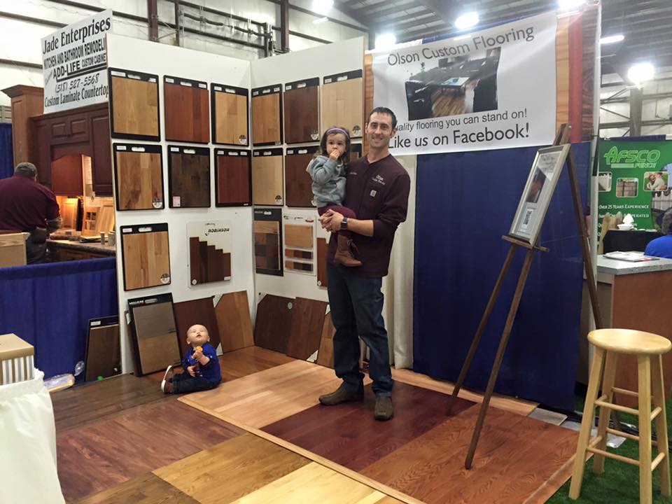 Man posing with two young children in an Olson Custom Flooring display